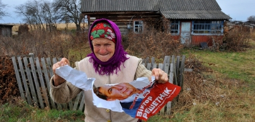 Ukrajinská vesničanka trhá volební plakát. Asi se jí nelíbí kandidát.