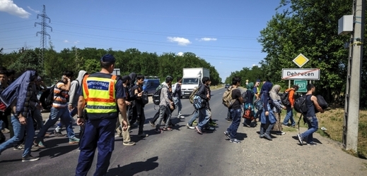 Policisté pomáhají skupině nelegálních migrantů přejít silnici nedaleko uprchlického tábora v Debrecínu.