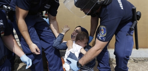 Syrská matka s dítětem a kolem ní maďarští policisté.